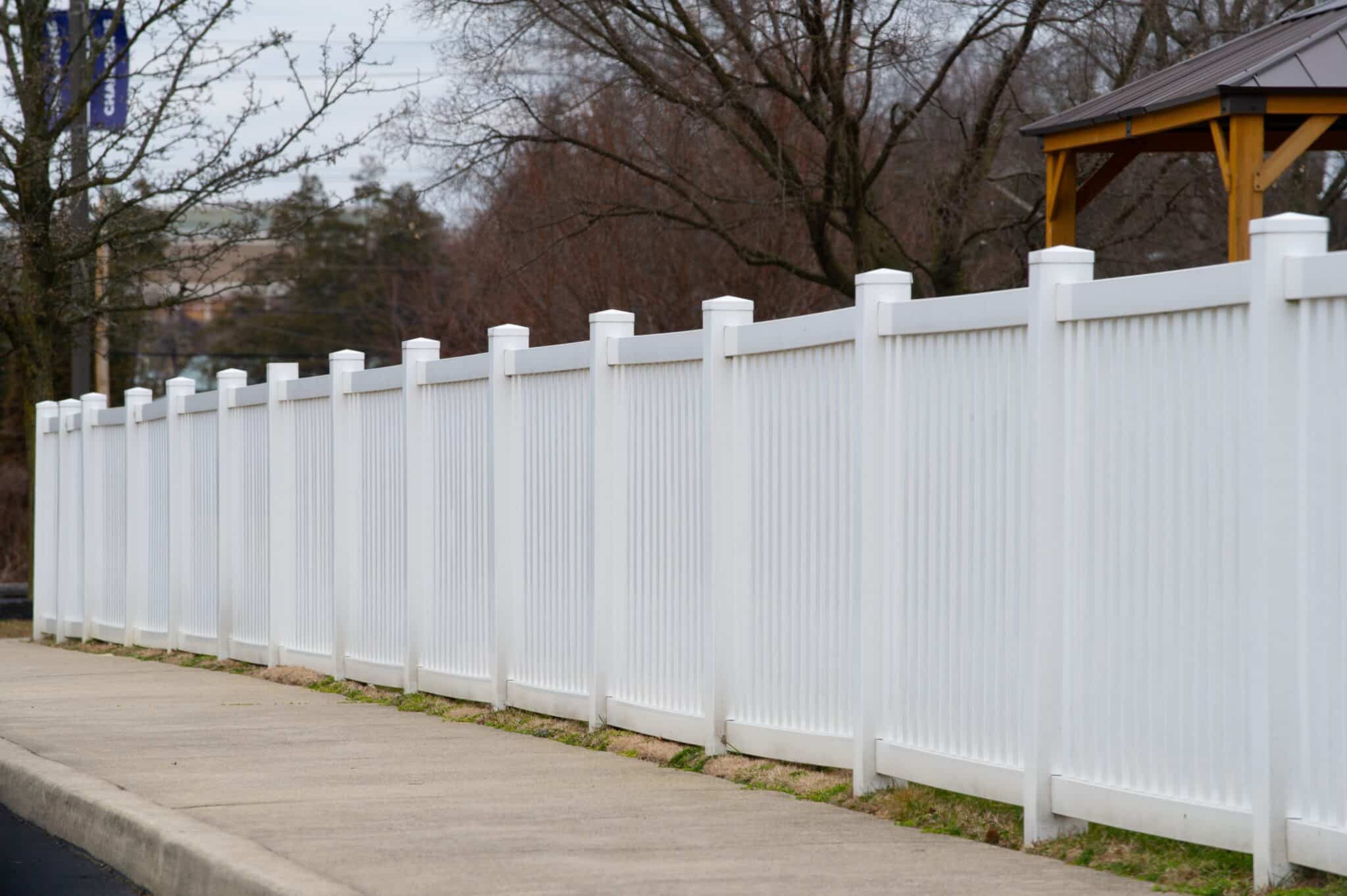 A tall white vinyl privacy fence enclosing a commercial property, providing security and aesthetic appeal.