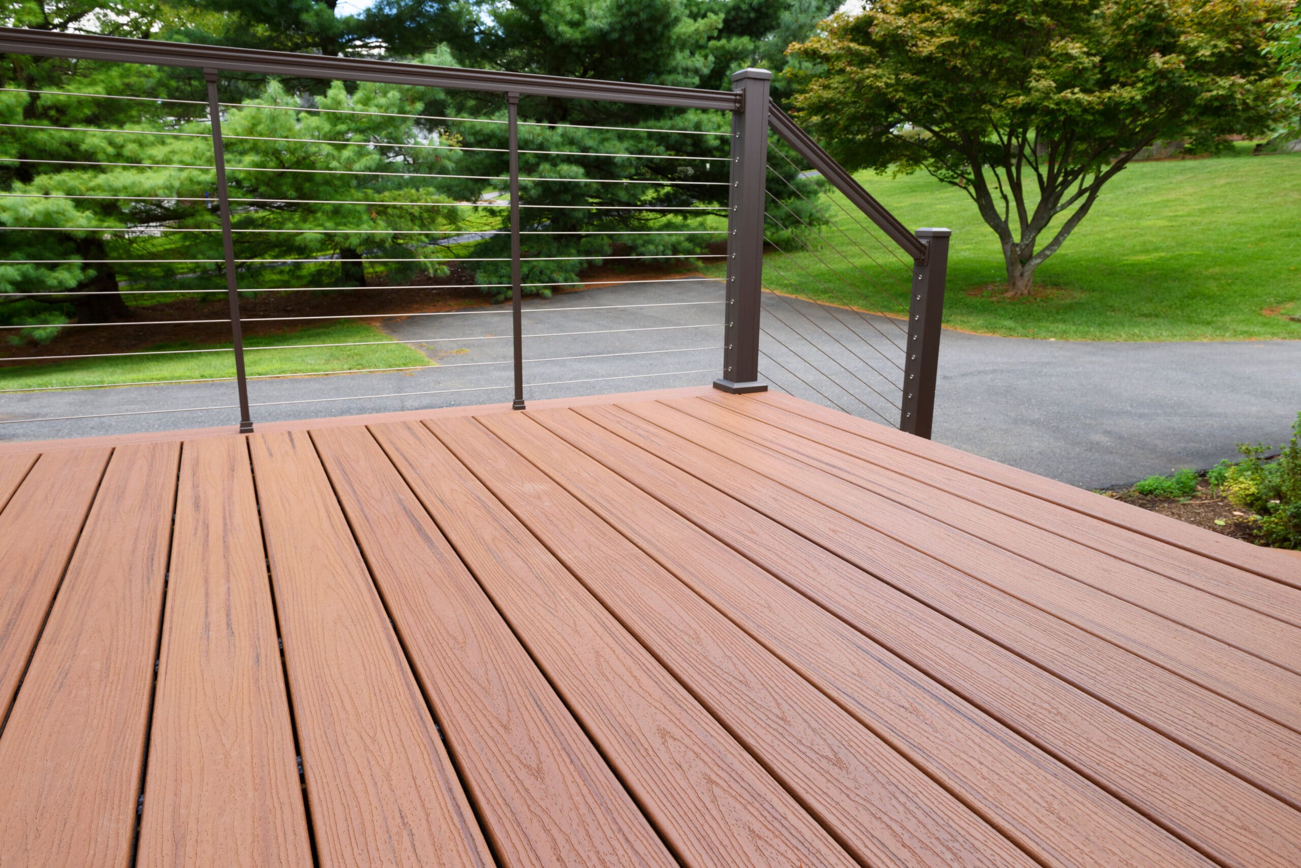 A spacious deck with brown composite wood flooring and sleek cable railing, installed by a professional railing installation near me service.